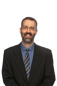 Eric James stands in front of a white background, smiling at the camera.